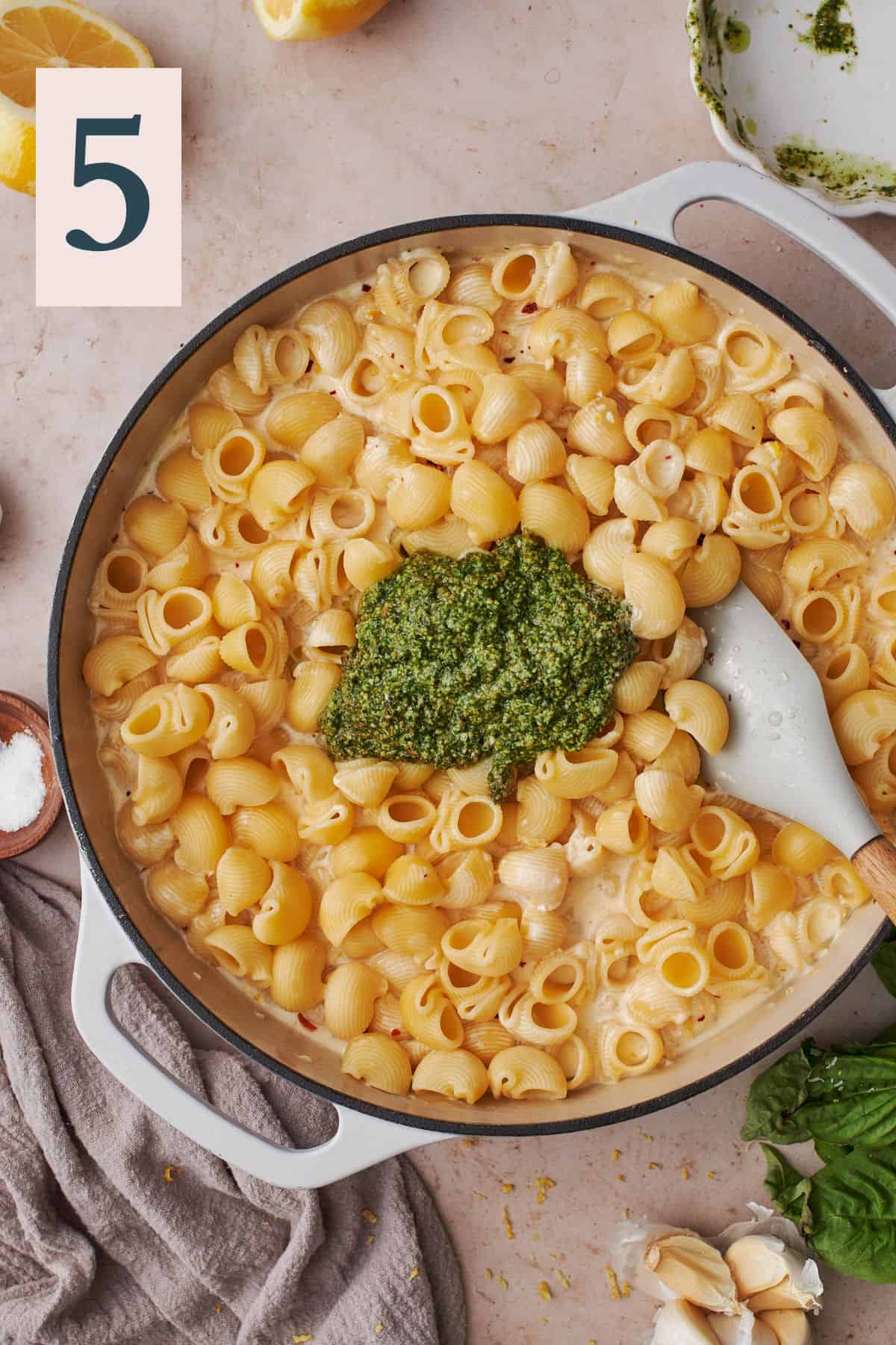cooked pasta in a skillet with fresh pesto added. 