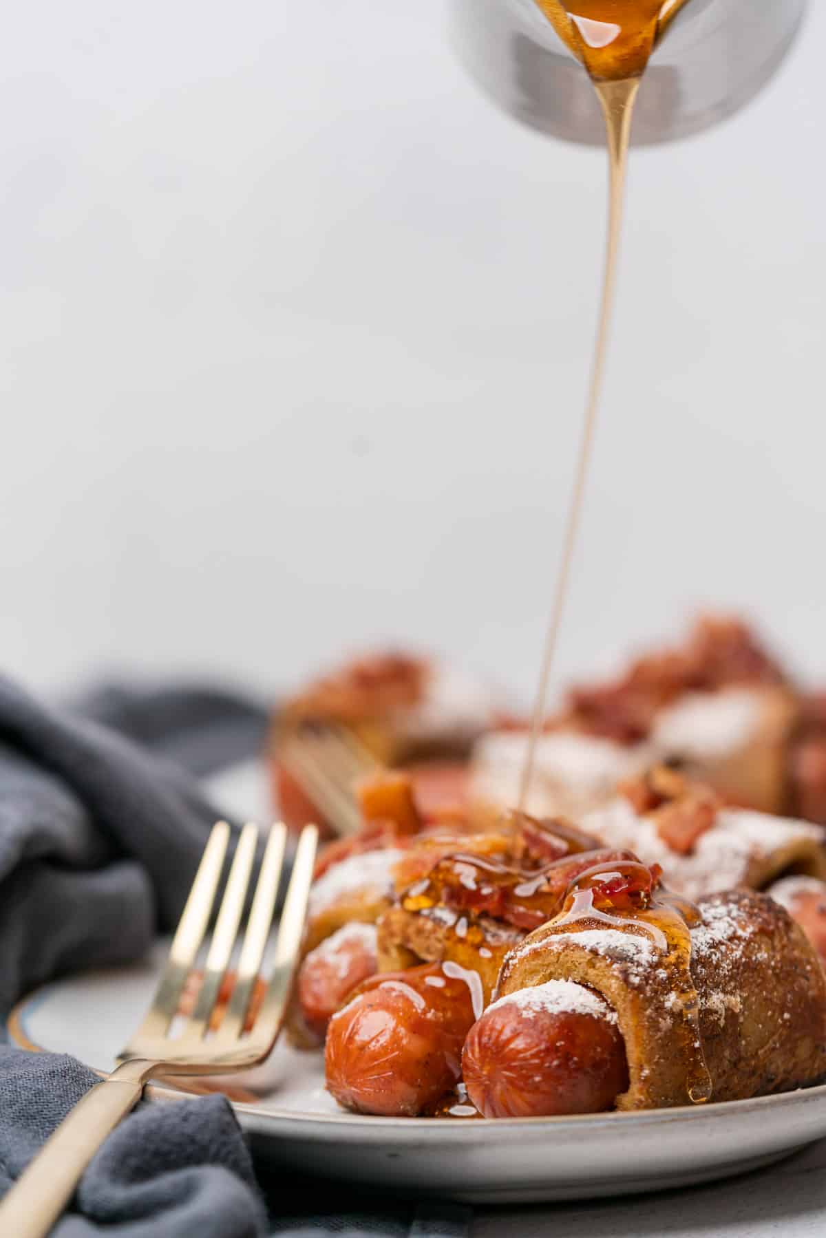 keto french toast pigs in a blanket being drizzled with sugar free maple syrup
